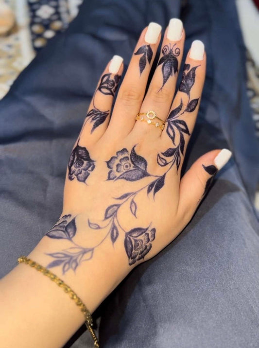 Deep blue-black jagua tattoo with floral rose and vine design covering the back of a hand and fingers