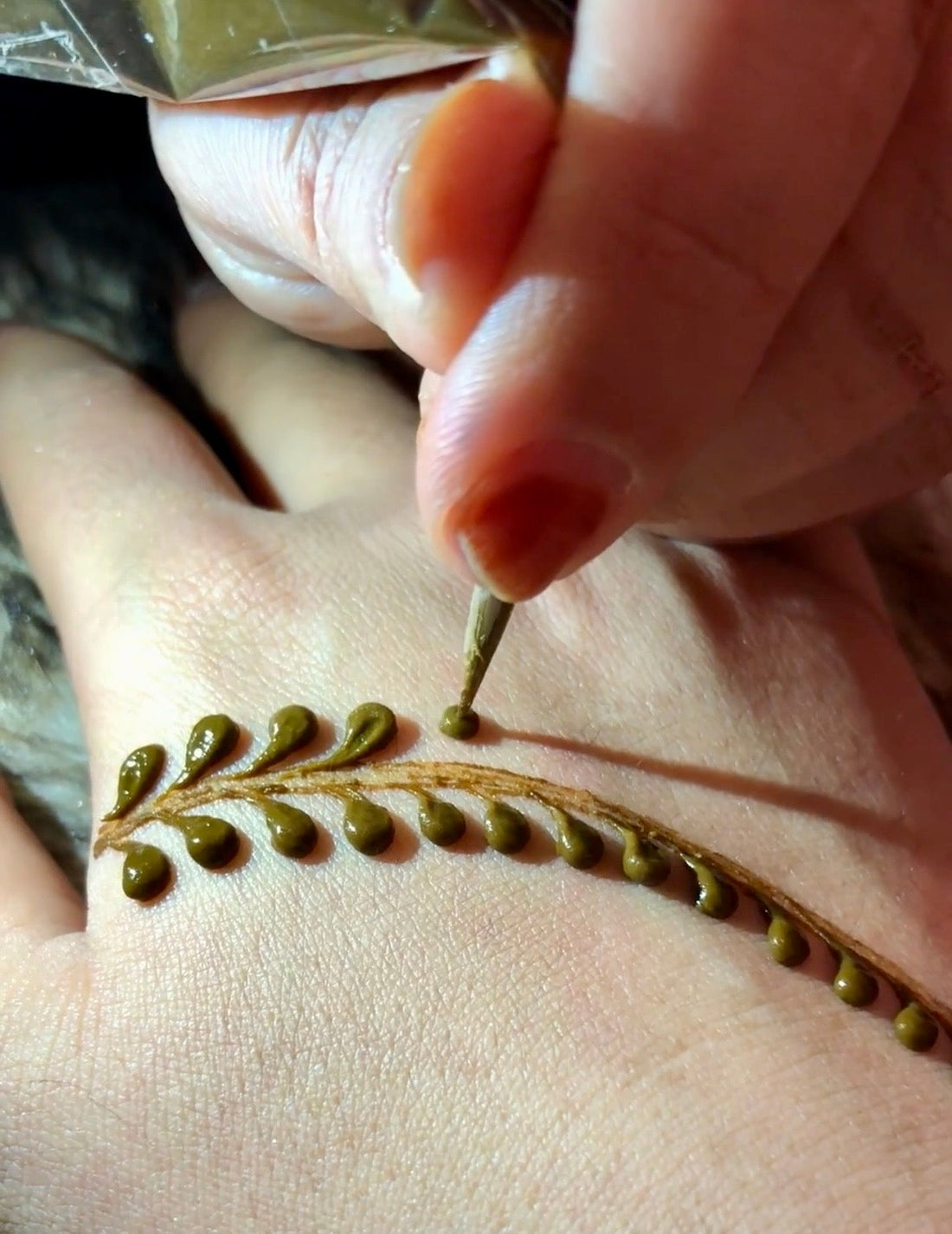 How to hold a henna cone correctly, showing hand position and tip control for beginners
